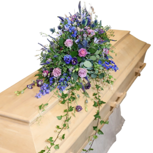 Kista av trä dekorerad med ett blomsterarrangemang i lila och rosa nyanser.